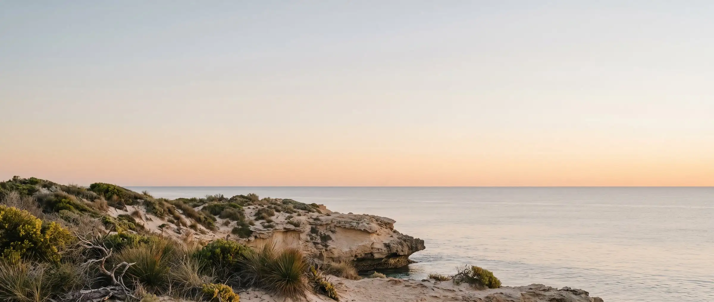 A limestone headland and a calm ocean horizon at golden hour