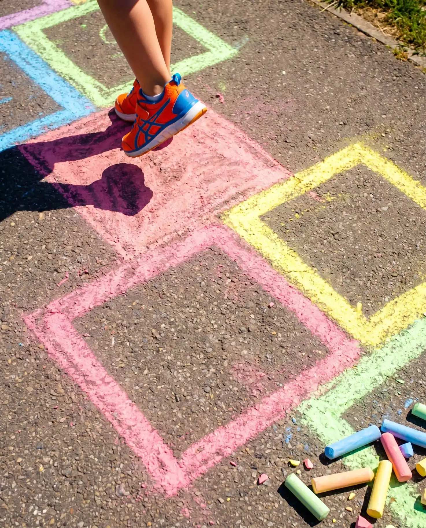 A small sneaker hopping across a chalk hopscotch in pink, yellow, blue and green