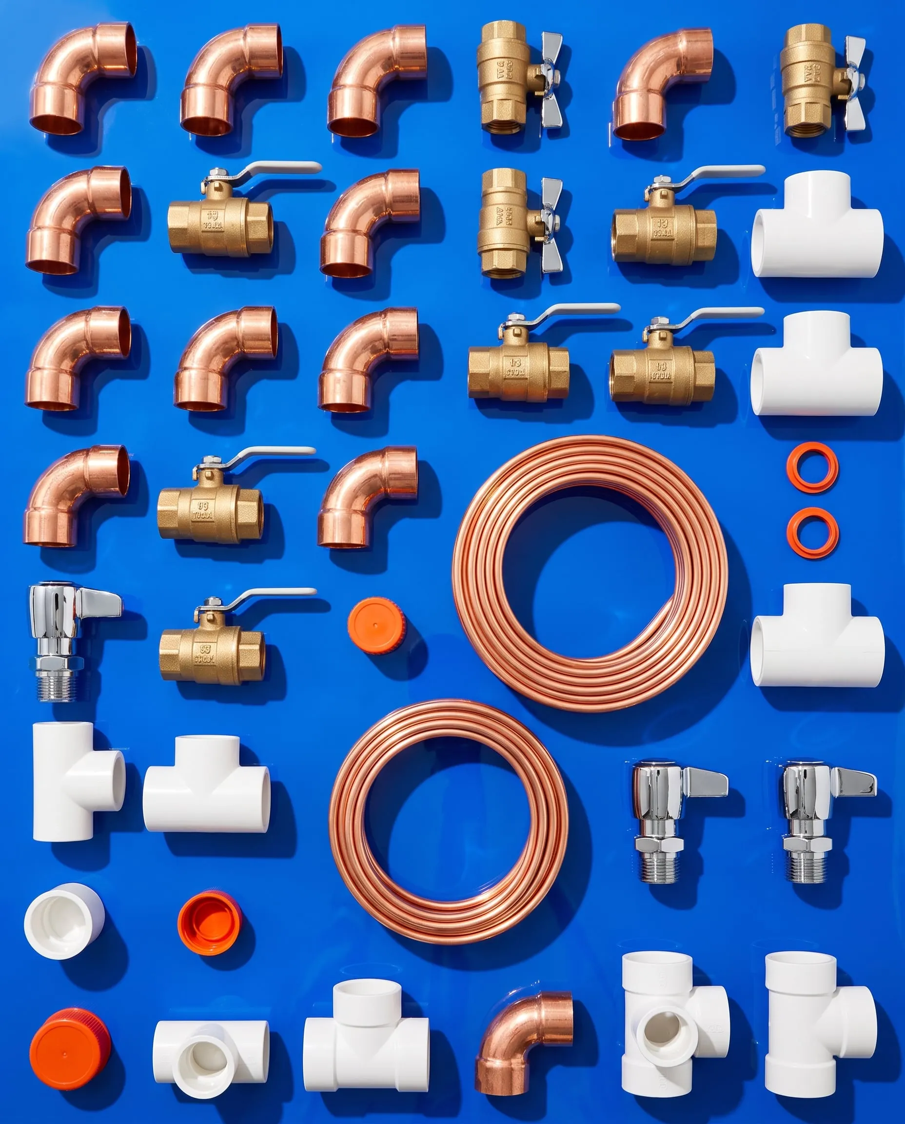 New copper, brass and white plumbing fittings laid out on a blue surface