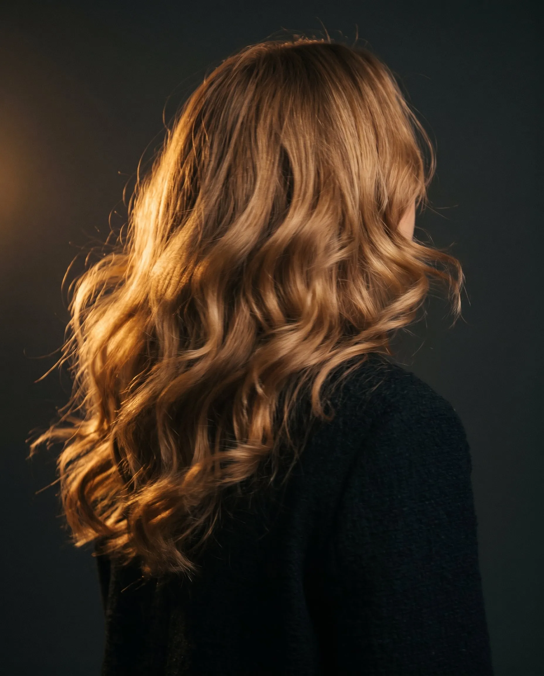 Big, soft blow-dried waves in caramel blonde, backlit by warm light