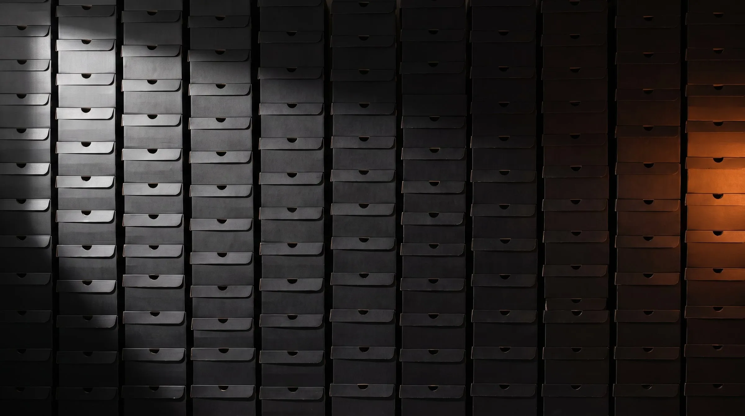 A wall of stacked black shoeboxes lit with an orange glow
