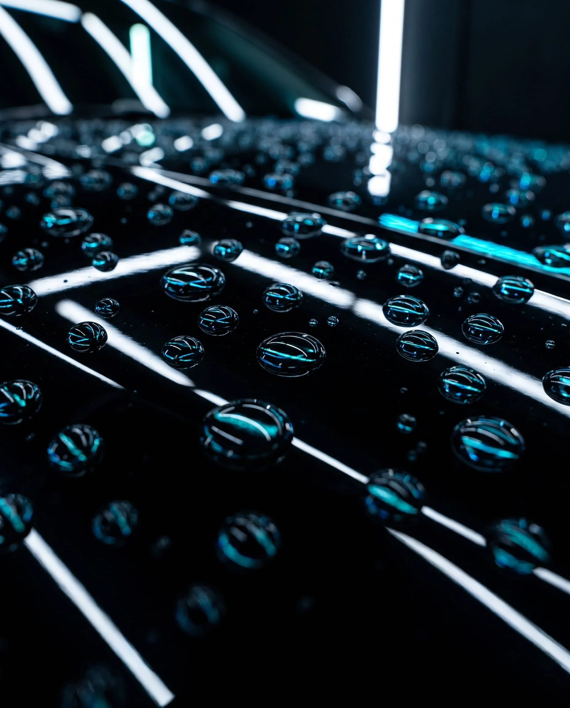 Water beading on coated black paint, cyan and white light reflected in the beads