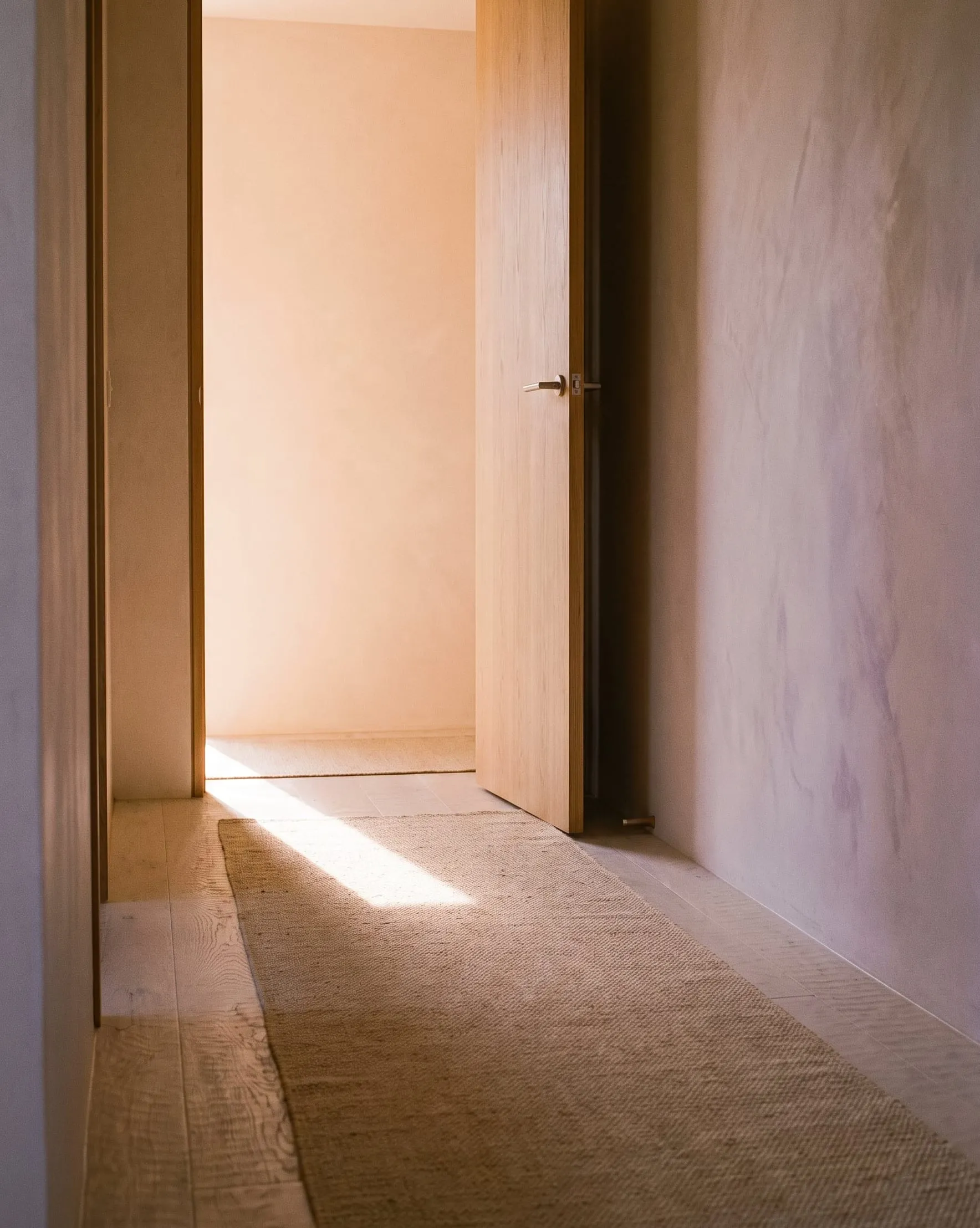 An oak door standing open onto a softly sunlit room.
