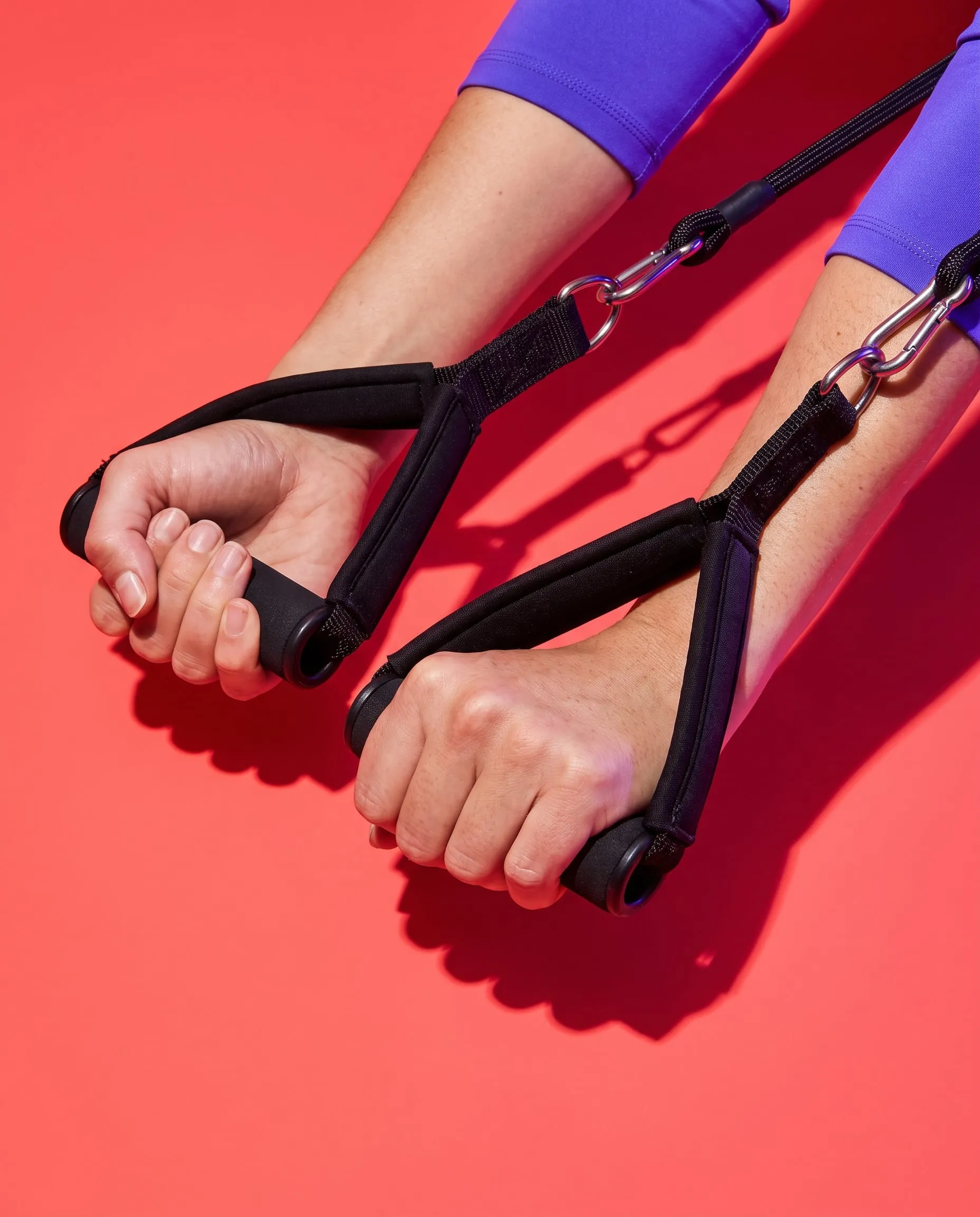 Hands gripping the padded handles of reformer straps