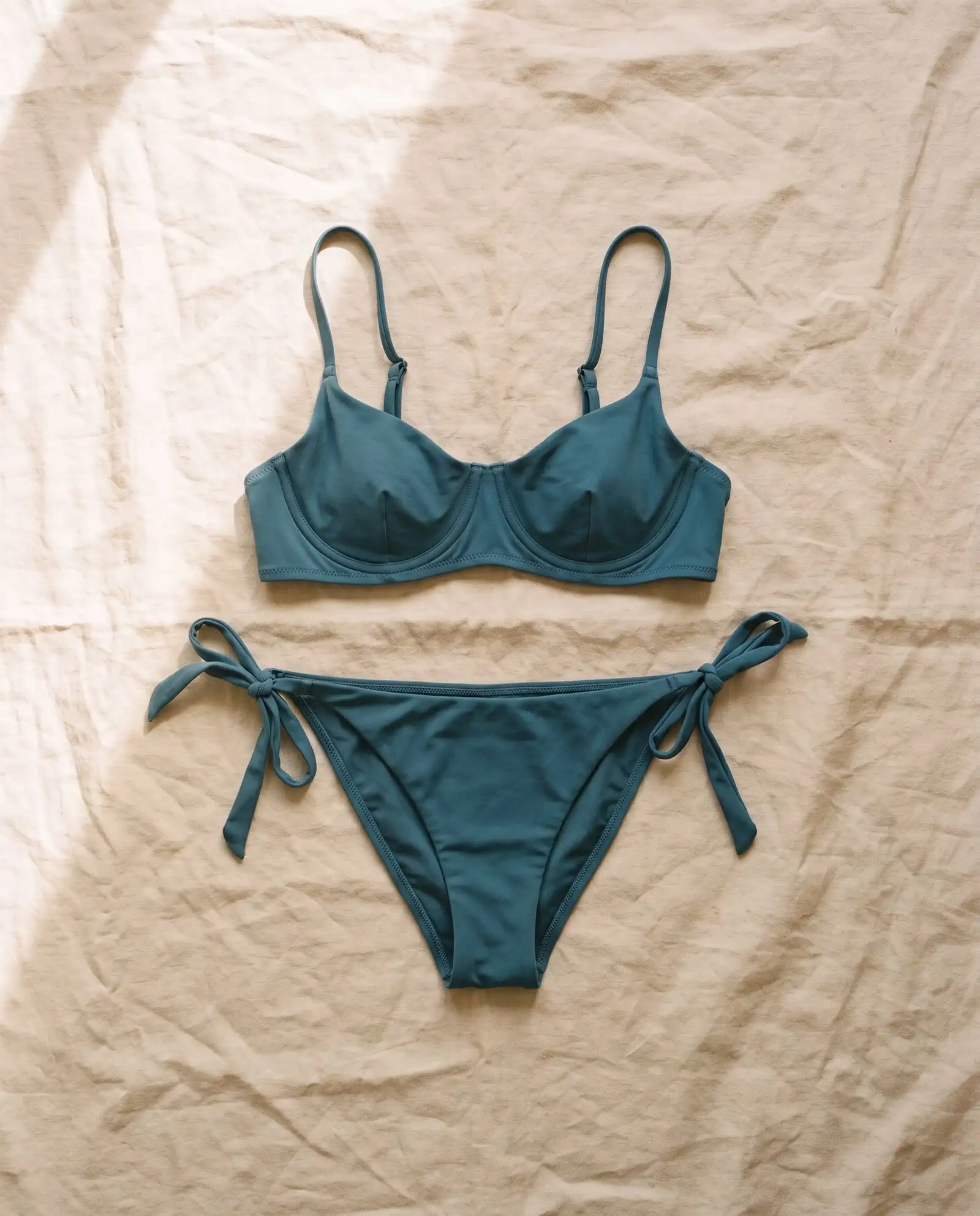 Belongil tie-side bikini set in Tidepool, laid flat on sand-coloured linen