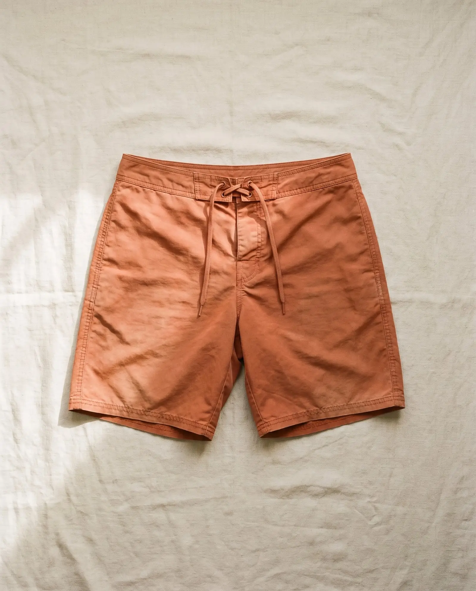 Suffolk boardshort in Ochre, laid flat on sand-coloured linen