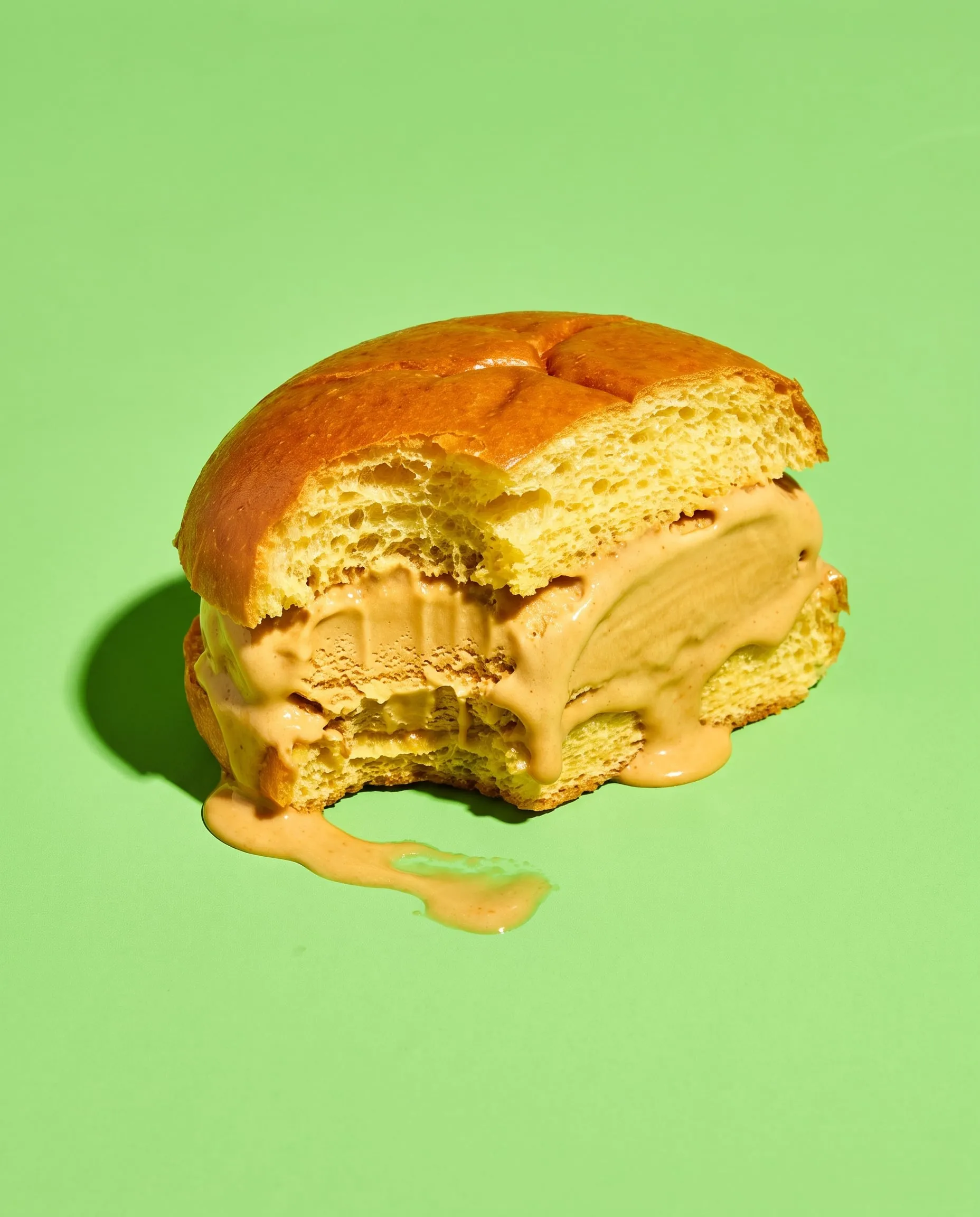 A gelato sandwich of salted caramel gelato in a soft brioche bun with a bite taken out