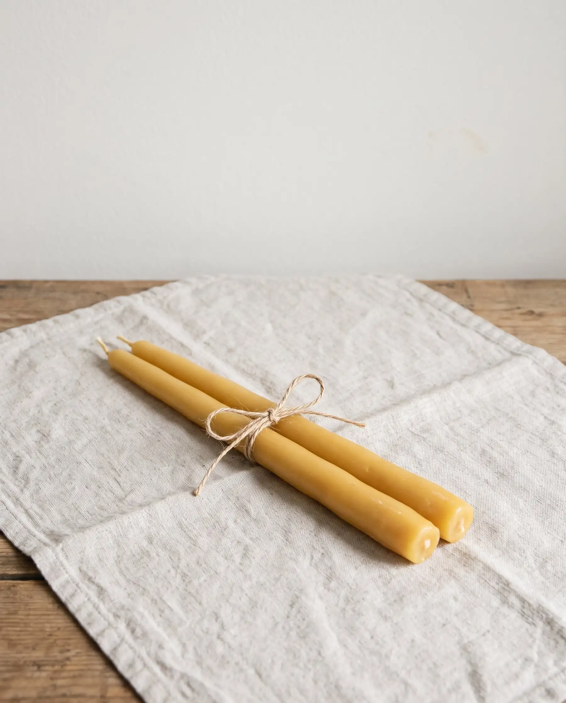 A pair of honey-coloured beeswax tapers tied with twine