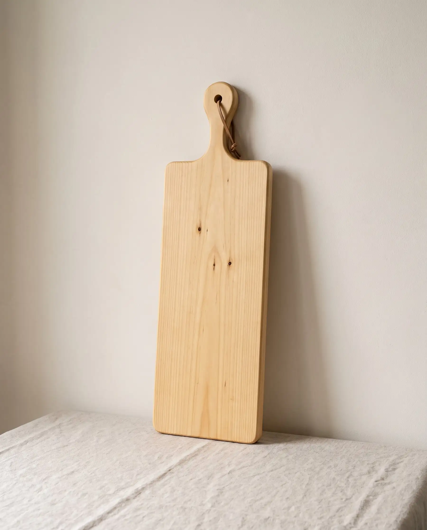 A long golden Huon pine serving board with a leather loop