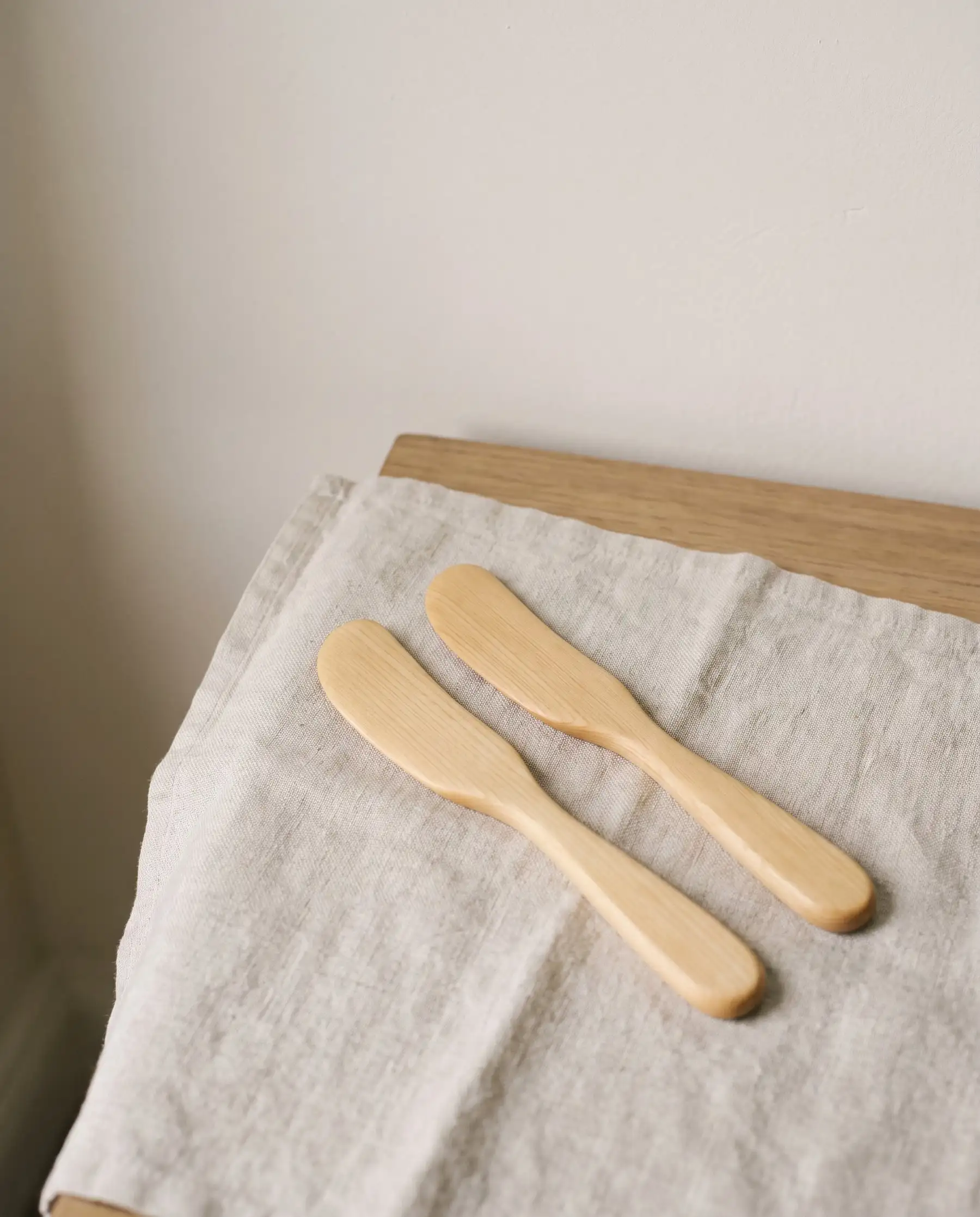 A pair of small Huon pine butter spreaders on linen